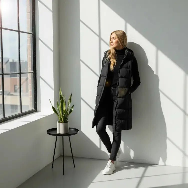 Parka femme : 10 modèles polyvalents et stylés 2025, femme en parka noire élégante près d'une fenêtre.