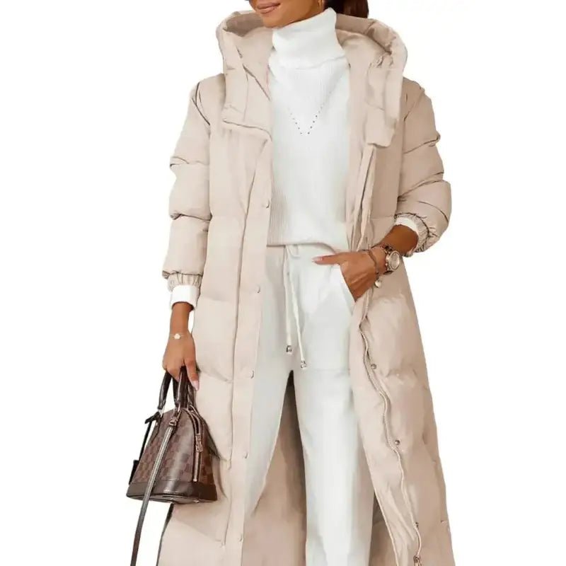 Parka longue femme kaki matelassée portée avec un ensemble blanc et un sac élégant.