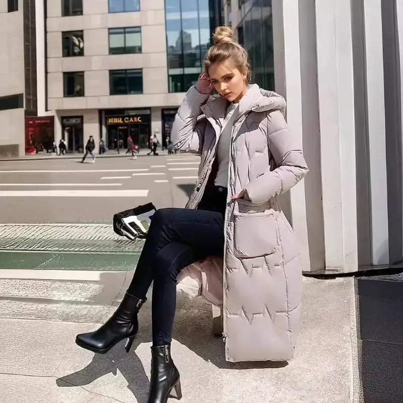 Parka femme matelassée hiver longue en couleur beige portée avec des bottines noires.