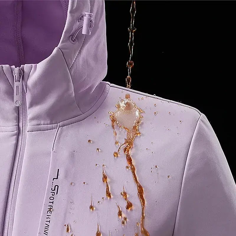 Parka femme à capuche cintrée en tissu déperlant, montrant des gouttes d'eau sur une surface rose.