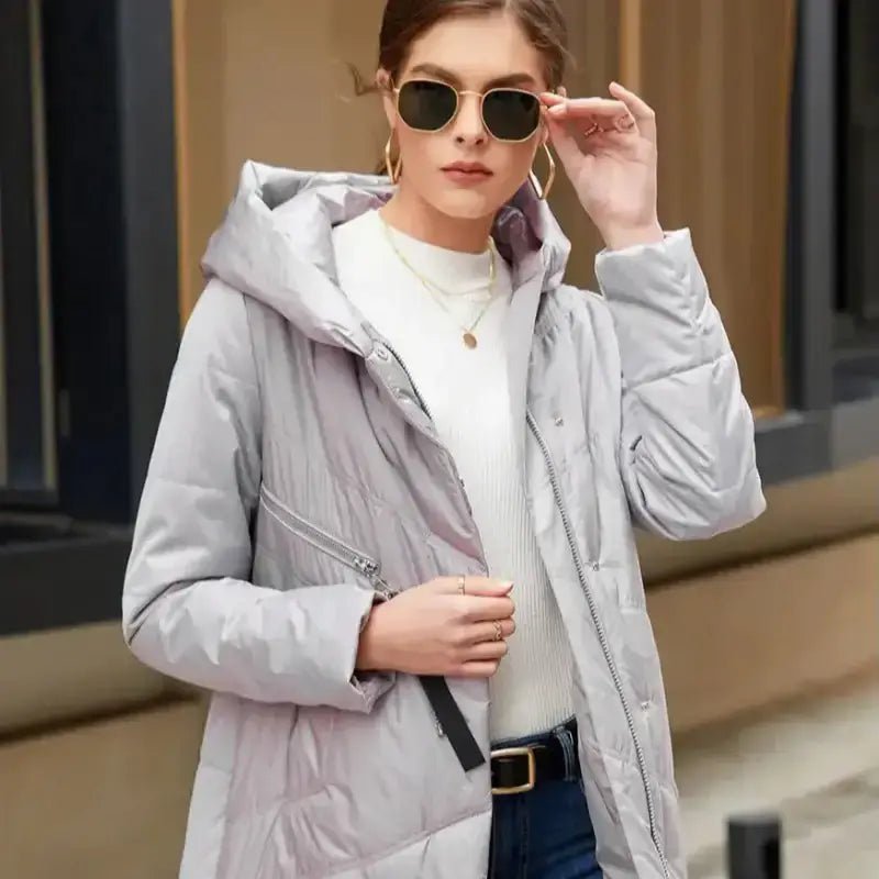 Parka longue femme matelassée à capuche portée par un modèle avec lunettes de soleil.