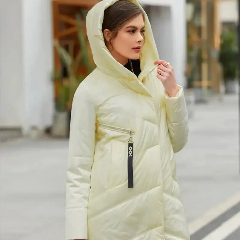 Femme portant une parka longue pour femme jaune clair avec capuche, idéale pour l'hiver, sur un fond urbain.