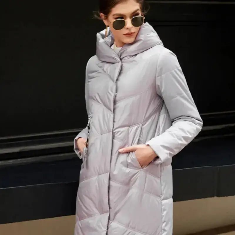 Parka longue femme matelassée à capuche en polyester gris portée avec lunettes de soleil.