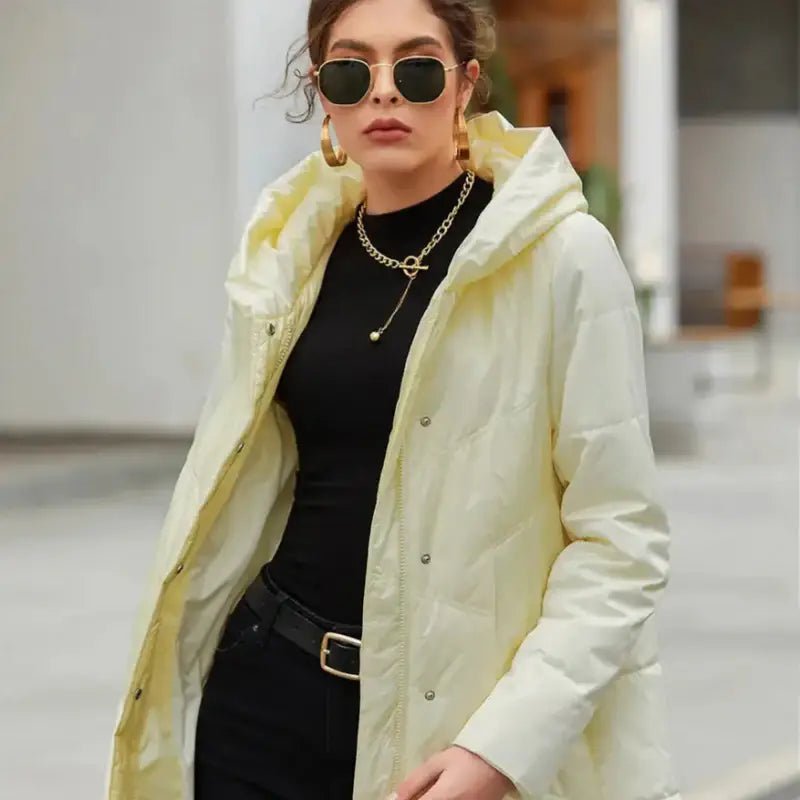 Femme portant une parka longue pour femme jaune, lunettes de soleil et bijoux en extérieur.