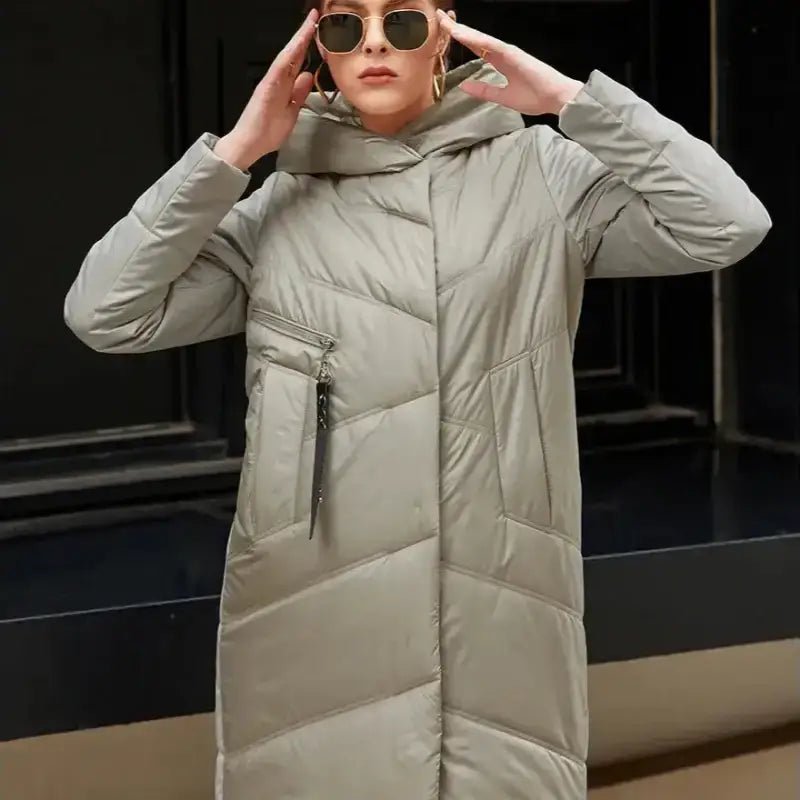 Parka longue femme matelassée à capuche couleur gris avec lunettes de soleil.