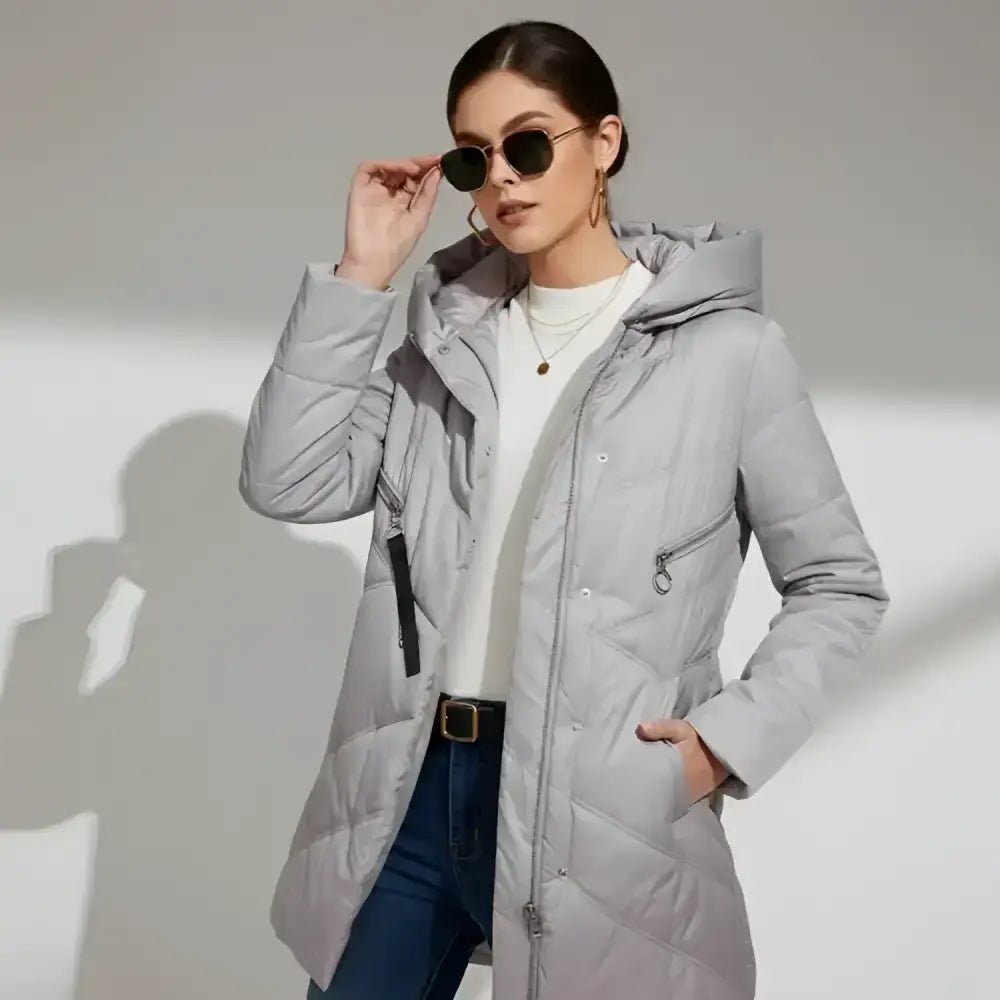 Femme portant une parka longue femme matelassée grise avec capuche et lunettes de soleil.